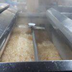 Close up of maple sap rapidly boiling inside a stainless steel evaporator during syrup production.